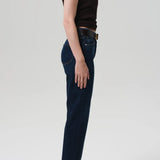 Side view of blaine jean in medina on model wearing black and brown tank tops with black heels, against a white background.