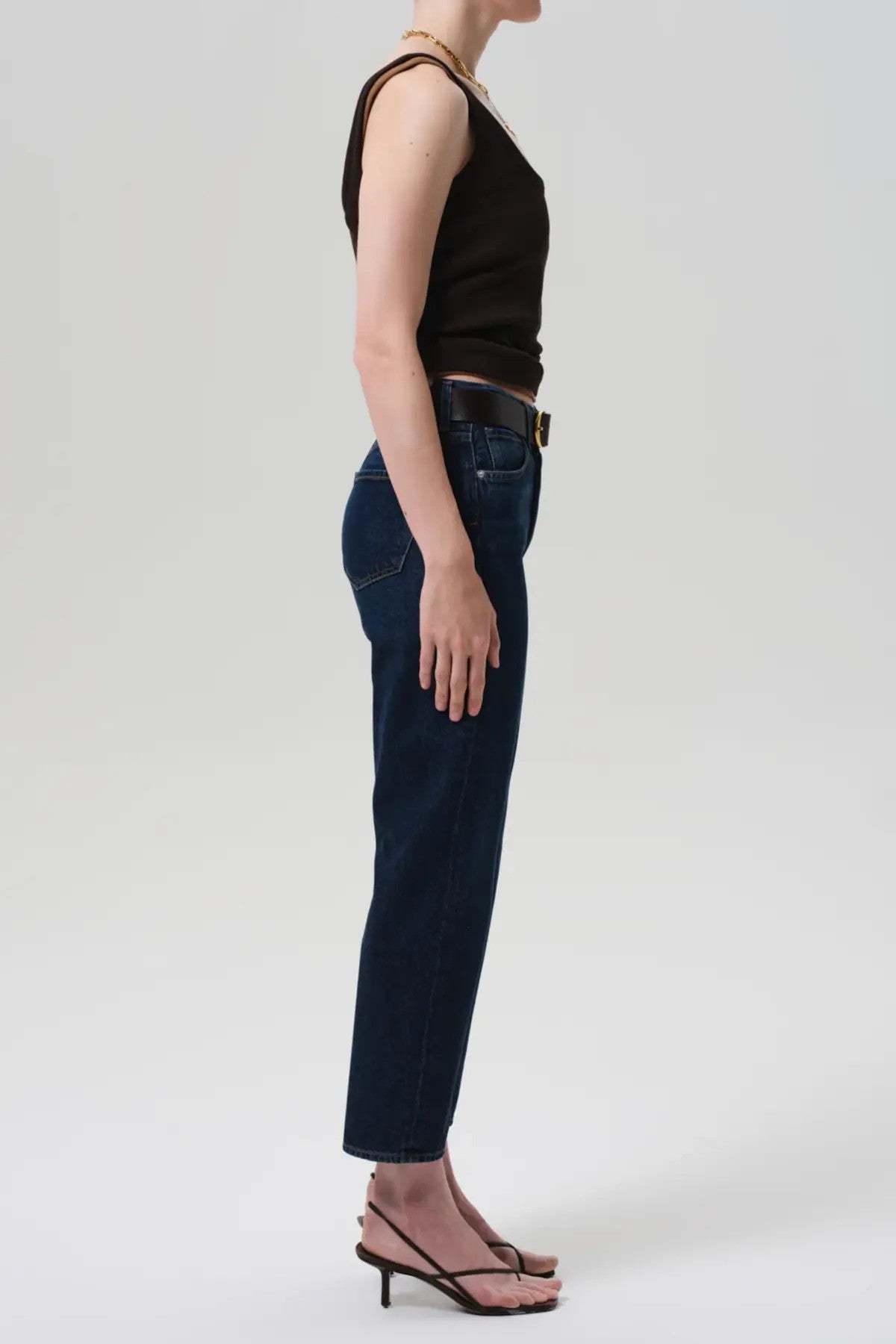 Side view of blaine jean in medina on model wearing black and brown tank tops with black heels, against a white background.