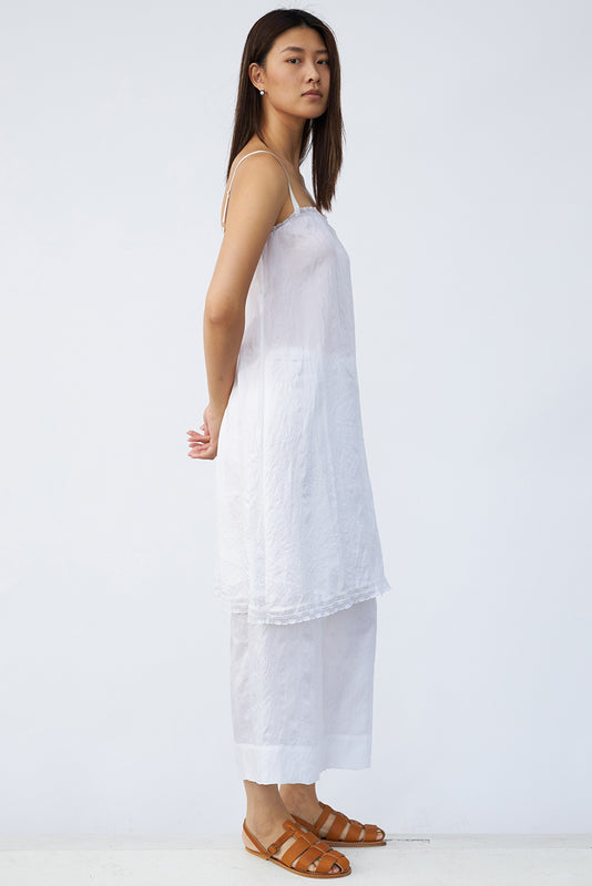 Side view of rice chemise slip on model wearing rice pants and natural sandals, against a white background.