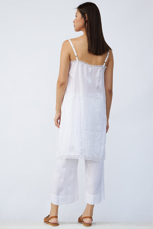 Back view of rice chemise slip on model wearing rice pants and natural sandals, against a white background.