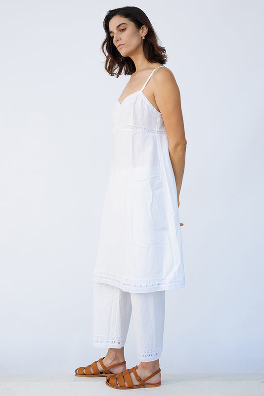 Side view of rice kymber slip on model wearing rice pants and natural sandals, against a white background.