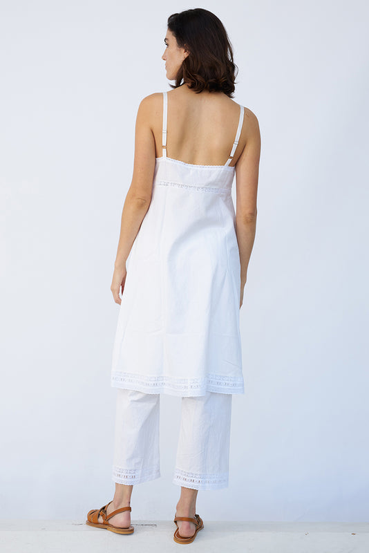 Back view of rice kymber slip on model wearing rice pants and natural sandals, against a white background.