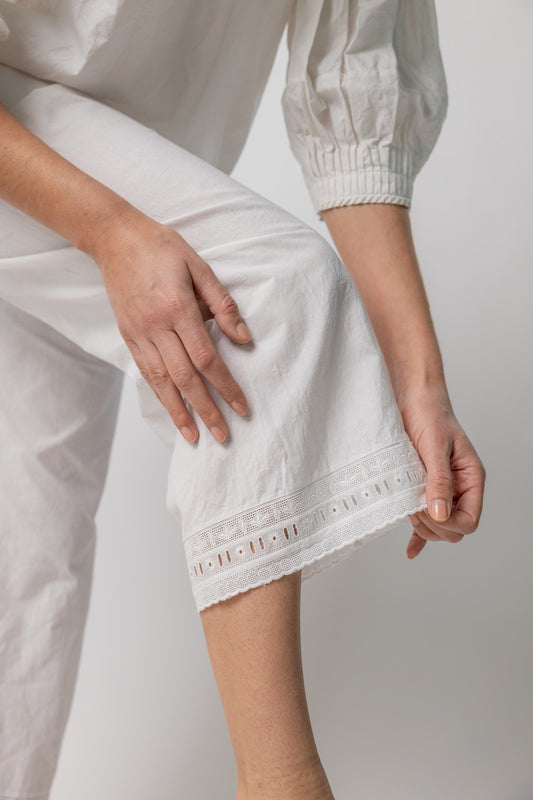 Bottom Hem closeup of rice pants with lace on model wearing rice top, against a white background.