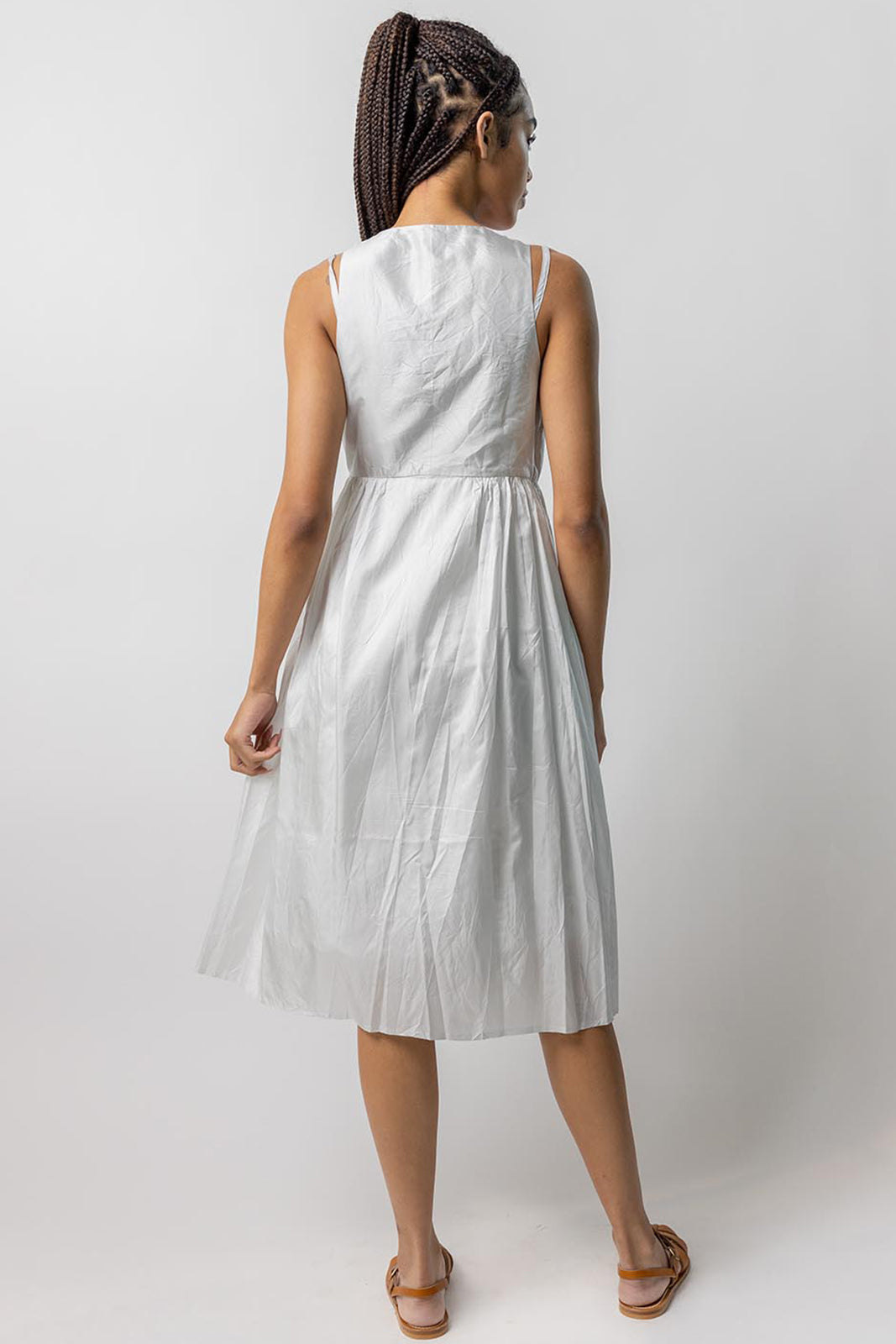 Back view of tint rajasthani dress on model wearing natural sandals, against a white background.