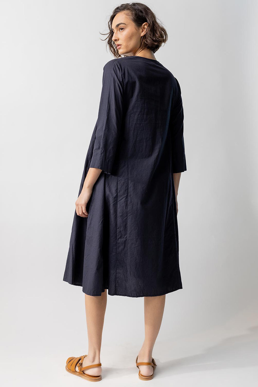 Back view of midnight short tule dress on model wearing natural sandals, against a white background.