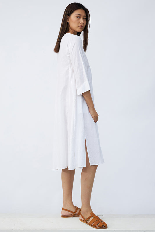 Side view of rice short tule dress on model wearing natural sandals, against a white background.