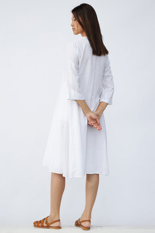 Back view of rice short tule dress on model wearing natural sandals, against a white background.