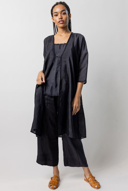 Front view of midnight wrap dress worn open on model wearing midnight pants and natural sandals, against a white background.