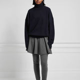 Front view of felt girl skirt on model wearing grey leggings, a navy pullover, and black loafers.