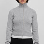 Front view of full zip grey sweater on model wearing white t-shirt and black pants, against a white background.