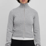 Front view of full zip grey sweater on model wearing white t-shirt and black pants, against a white background.