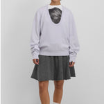 Front view of heaven jacob sweater on model wearing white printed shirt and grey skirt with white socks and red mary janes, against a white background.