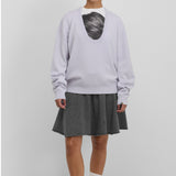 Front view of heaven jacob sweater on model wearing white printed shirt and grey skirt with white socks and red mary janes, against a white background.