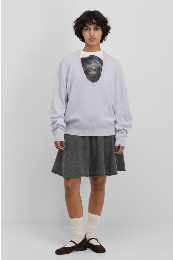 Front view of heaven jacob sweater on model wearing white printed shirt and grey skirt with white socks and red mary janes, against a white background.