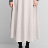 Front view of chalk no 388 ease skirt on model wearing grey sweater and black heels, against a white background.