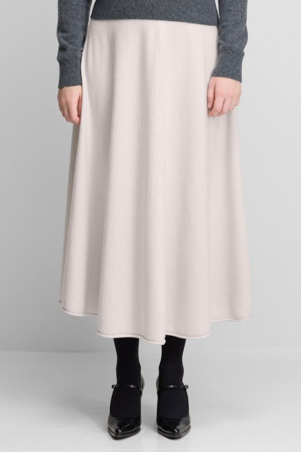 Front view of chalk no 388 ease skirt on model wearing grey sweater and black heels, against a white background.