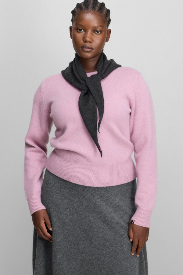 Front view of rosa no 430 jeanne sweater on model wearing grey skirt, against a white background.