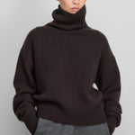 Front view of dark brown no 434 crop xtra sweater on model wearing grey pants, against a white background.