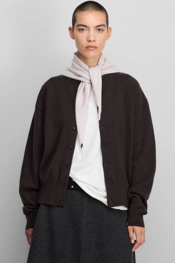 Front view of dark brown no 436 luce cardigan on model wearing white shirt and grey skirt, against a white background.