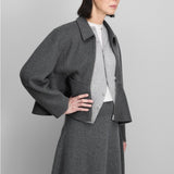Front view of felt no 442 queen coat on model wearing grey skirt and light grey sweater, against a grey background.