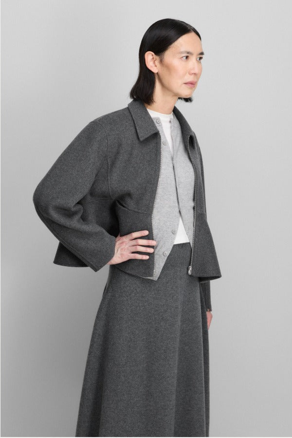 Front view of felt no 442 queen coat on model wearing grey skirt and light grey sweater, against a grey background.