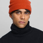 Front view of dark orange no 444 hat on model wearing raven sweater, against a white background.