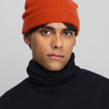 Front view of dark orange no 444 hat on model wearing raven sweater, against a white background.