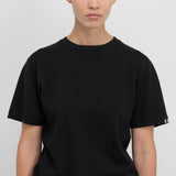 Front view of raven cuba top on dark- haired model in grey pants, against white background