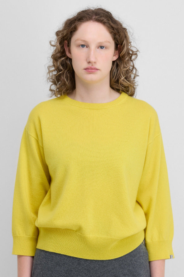 Front view of sunny jewel sweater on model wearing grey trousers, against a white background.