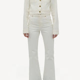 Front view of white ezra bootcut jean on model wearing white jean jacket and boots, against a white background.