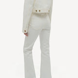 Back view of white ezra bootcut jean on model wearing white jean jacket and boots, against a white background.