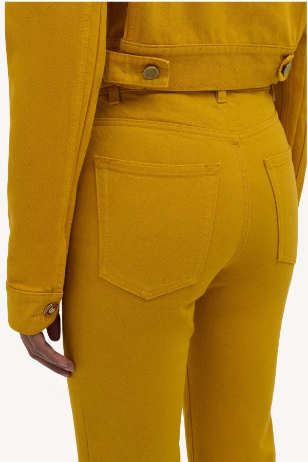 Back closeup view of golden birch ezra bootcut jean on model wearing golden birch jacket, against a white background.