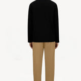 Back view of cammello laminar trousers on model wearing black t-shirt and sneakers, against a white background.