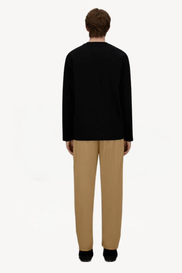 Back view of cammello laminar trousers on model wearing black t-shirt and sneakers, against a white background.