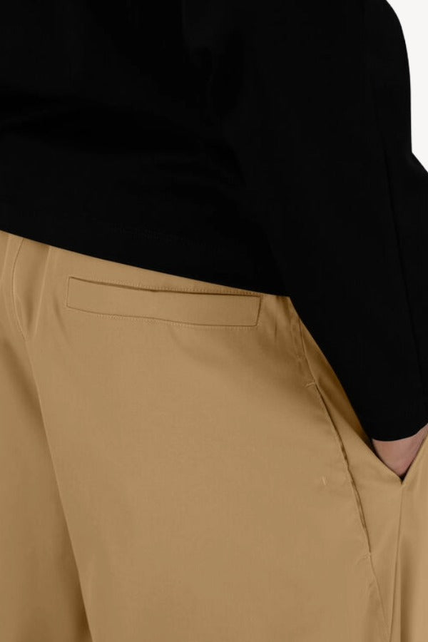 Back closeup view of cammello laminar trousers on model wearing black t-shirt, against a white background.