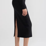 Side view of black geo petra skirt on model wearing black top and flats, against a white background.