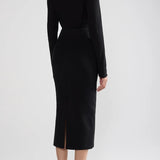 Back view of black geo petra skirt on model wearing black top and flats, against a white background.