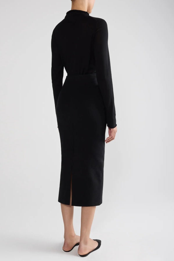 Back view of black geo petra skirt on model wearing black top and flats, against a white background.
