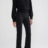 Front view of black lofty lara sweater on model wearing black pants and sandals, against a white background.