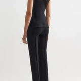 Back view of black combo windowpane inna top on model wearing black pants and flats, against a white background.