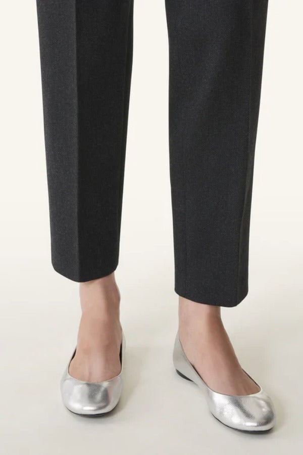 Front and side view of silver ballerina flats on model wearing black pants, against a white background.