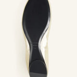 Sole view of gold ballerina flat on white background, with no model shown.