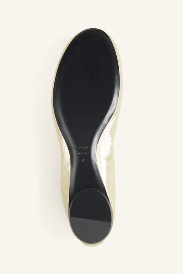 Sole view of gold ballerina flat on white background, with no model shown.