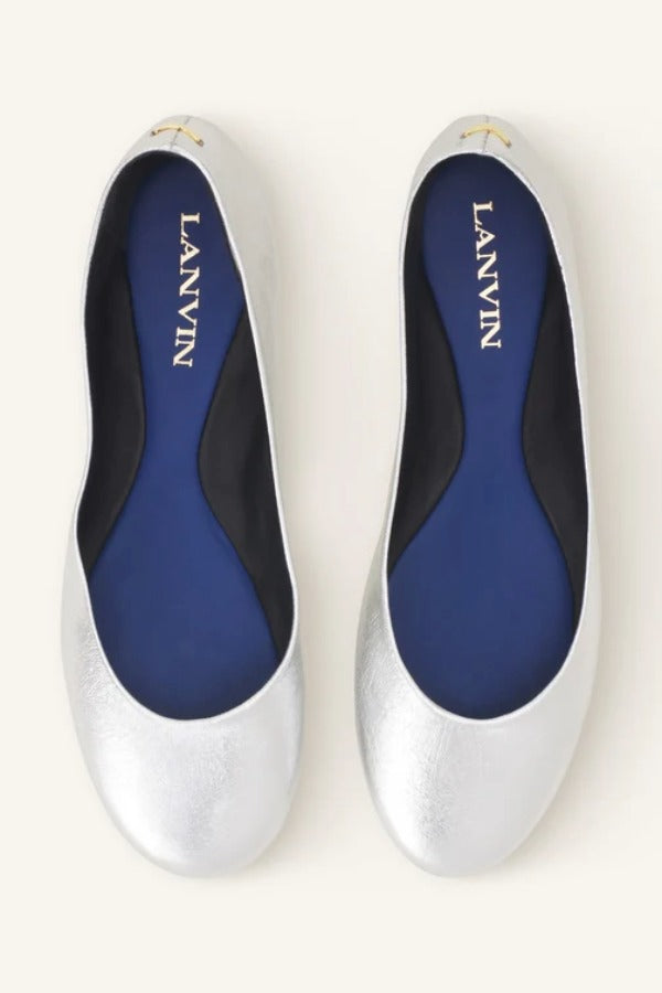 Overhead view of silver ballerina flats on white background, with no model shown.