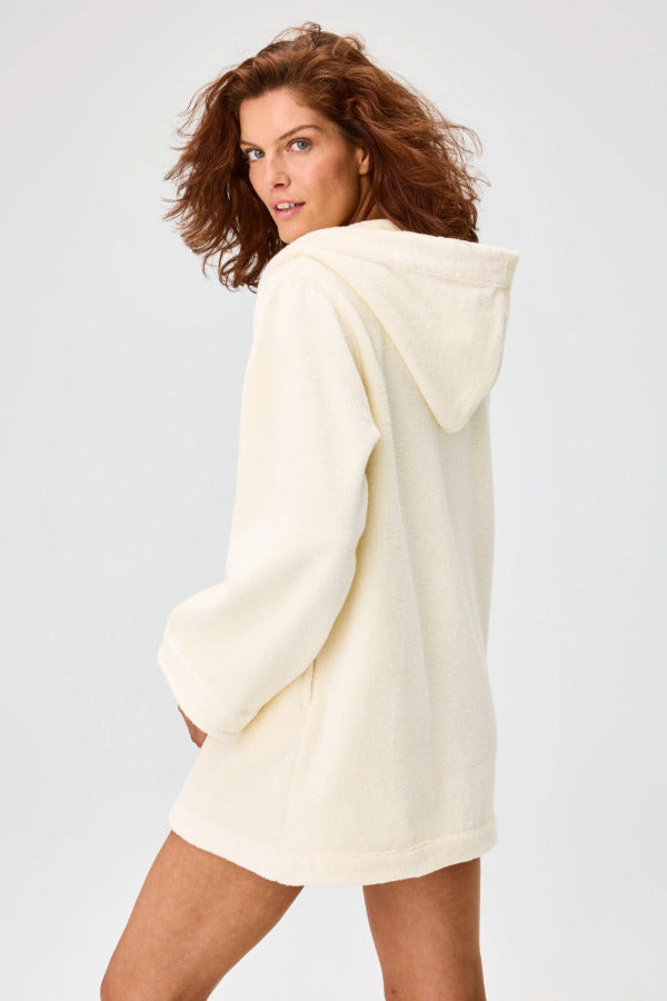 Back view of cream terry beach tunic on brown-haired model against a white background.