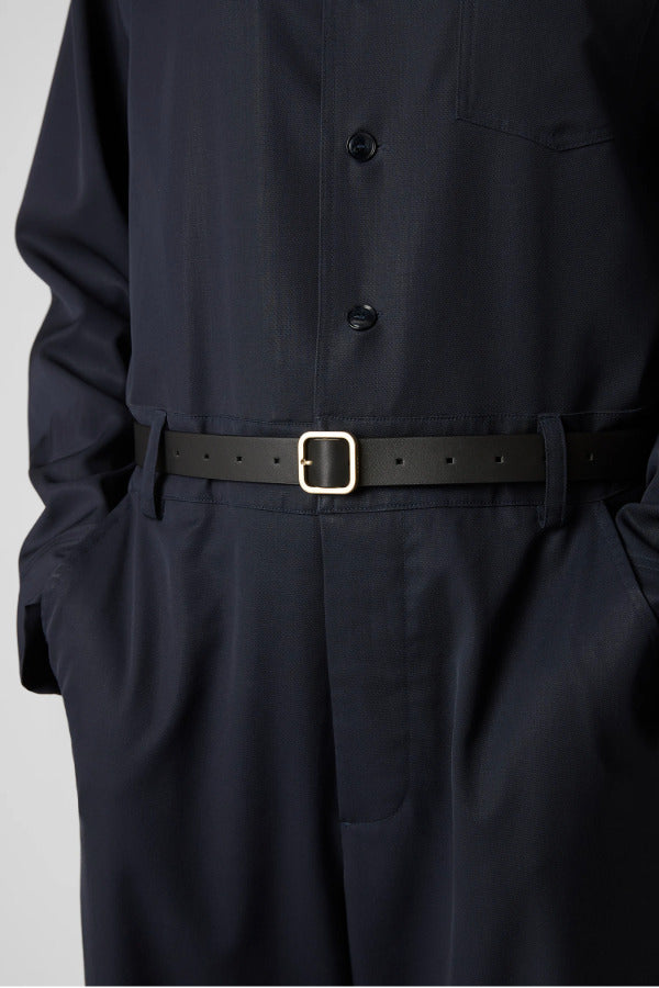 Front view of black marsell quadra belt on model wearing black shirt and trousers, against a white background.
