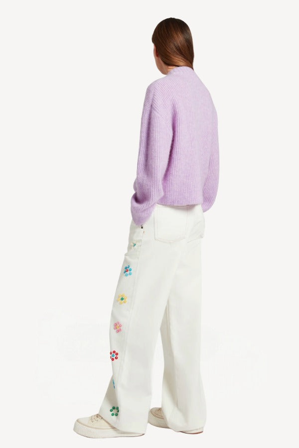 Back view of lilac embroidered sweater on model wearing white denim and sneakers, against a white background.