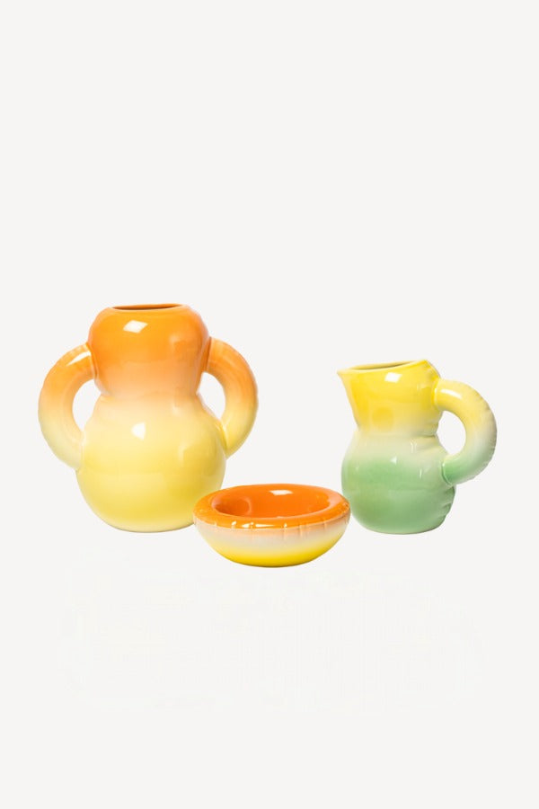 Front view of orange hand sprayed ombre vase aligned with other home goods, against a white background, with no model shown.