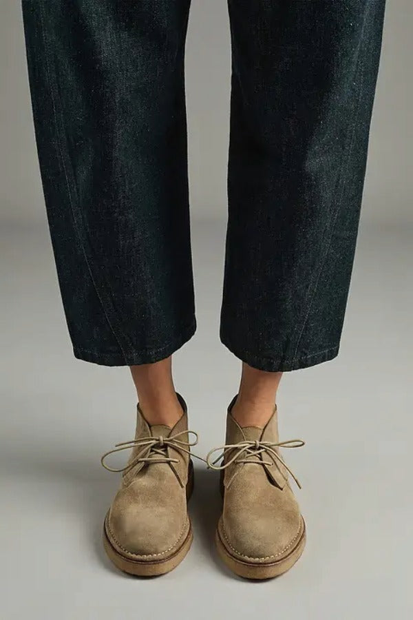 Front view of pair of sand antoine desert boots on model wearing cropped jeans, against a white background.