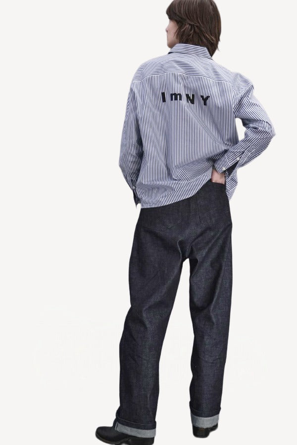 Alternate back view of blue white stripe imny shirt on model wearing dark jeans and boots, against a white background.